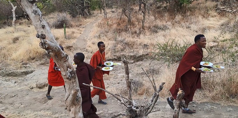 Masai ratnici u tradicionalnoj odeći u Masai Lodge-u, konobari donose hranu